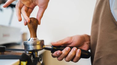 Bir elinde kahve tutarken erkek baristanın espresso yaparken çekilmiş fotoğrafı tutacakta öğütülmüş kahveye basacak.