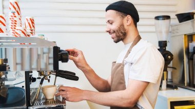 Kahve dükkanında başarılı bir sahibin kahve makinesini kullanışının yan görüntüsü. KOBİ girişimci işadamı konsepti