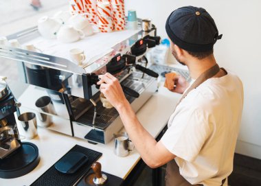 Kahvecide kahve makinesiyle kahve yapan erkek baristanın en iyi görüntüsü. Restoran yemekleri ve içki konsepti
