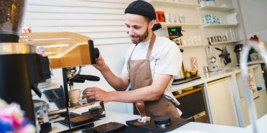 Kahve makinesini kahve yapmak için kullanan gülümseyen barista. Kahve işçisi kahve hazırlıyor. Hazırlık, servis kavramı
