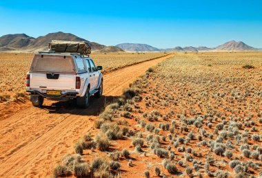 Pickup truck with roof tent is on an adventurous drive through the desert towards the Tiras mountains. Tiras, Namib, Namibia - 27 May 2022