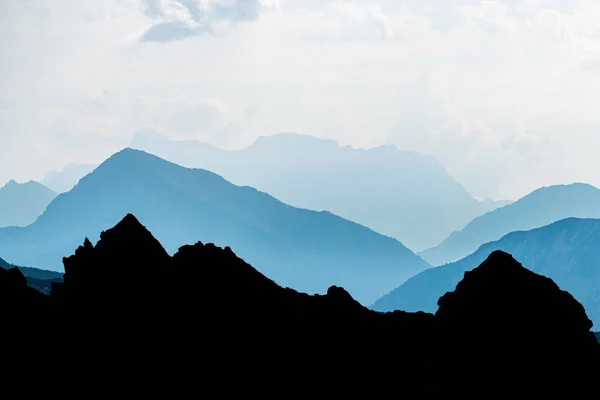 Blue Cyan Mountain Peaks Silhouette Bright Backlight Sunrise Alps Tirol Stockafbeelding
