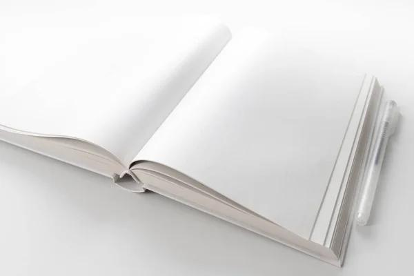 ペン付きの白い机の上に白いページがあるオープンブックの高い角度のビュー — ストック写真