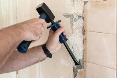 Eski kiremitleri mutfak duvarından çekiç ve keskiyle sökmek, yenileme konsepti