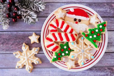 Bir tabak süslemeli Noel kurabiyesi. Kırsal ahşap arka planda, yukarıdan aşağıya manzara sahnesi. Tatil pişirme konsepti.