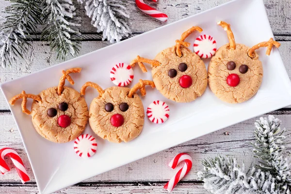 Christmas peanut butter red nose reindeer cookies. Overhead view table scene against a white wood background. Holiday baking concept.