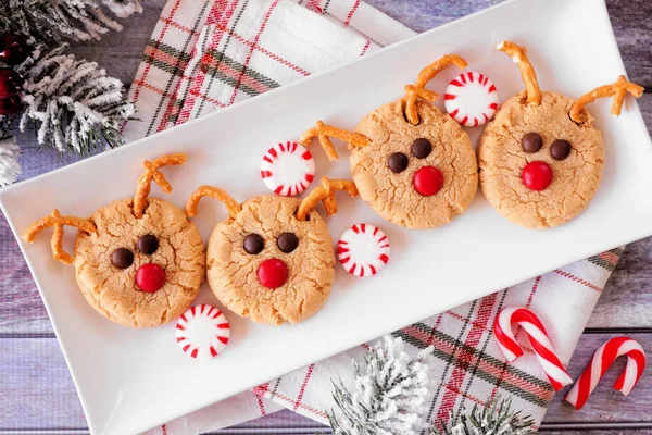Christmas peanut butter red nose reindeer cookies. Top down view table scene over a rustic wood background. Holiday baking concept.
