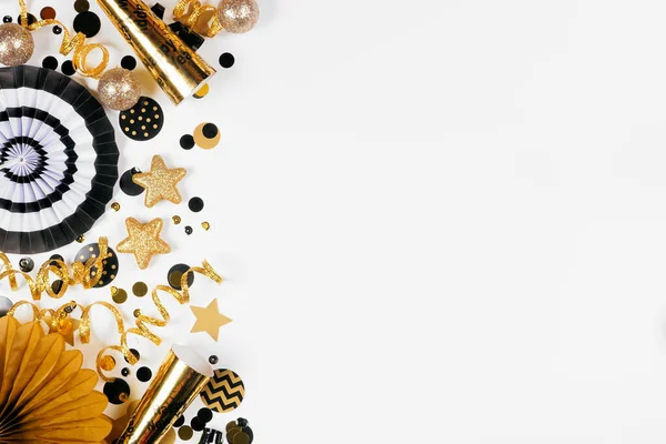 金と黒のコンフェッティ ノイズメーカー ストリーマーと装飾の大晦日側の国境 白い背景の上からの眺め — ストック写真