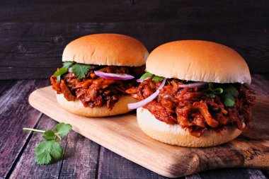 Jack fruit meatless burgers against a dark wood background. Healthy eating, plant-based pulled pork meat substitute concept.