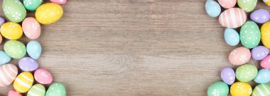 Colorful pastel Easter egg double border. Top view on a light wood banner background. Copy space.