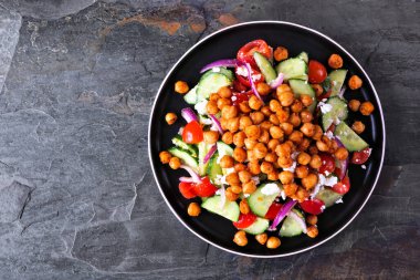 Healthy Mediterranean salad with chick peas. Top view over a dark slate background.