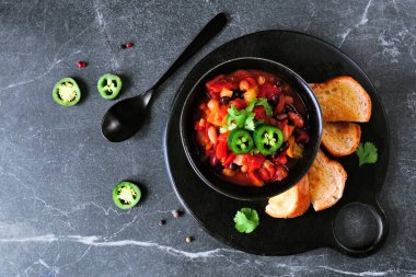 Homemade vegetarian chili with garlic bread. Overhead view table scene on a dark slate background.