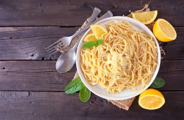 Taze limon ve parmesan peyniri soslu spagetti makarna. Koyu ahşap zemin üzerinde malzeme çerçevesi ile üst görünüm.