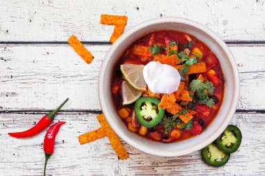 Domatesli tavuklu tortilla çorbası ve siyah fasulye. Meksika yemeği. Beyaz ahşap arka planda tepeden aşağı görünüm.