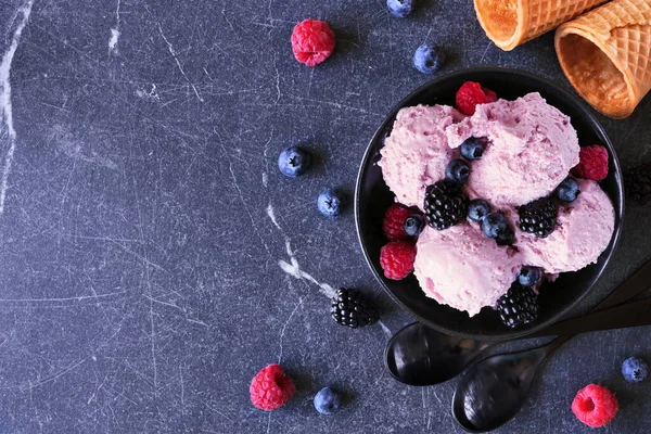 Bowl of field berry ice cream. Overhead view table scene with copy space over a dark stone background.
