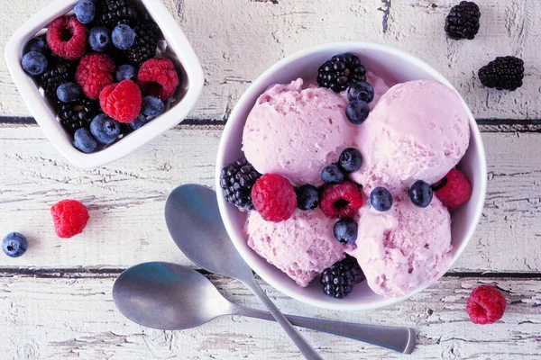 Bowl of field berry ice cream. Overhead view table scene over a white wood background.