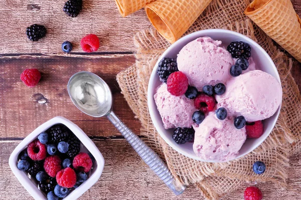 Bowl of field berry ice cream. Above view table scene with over a rustic wood background.