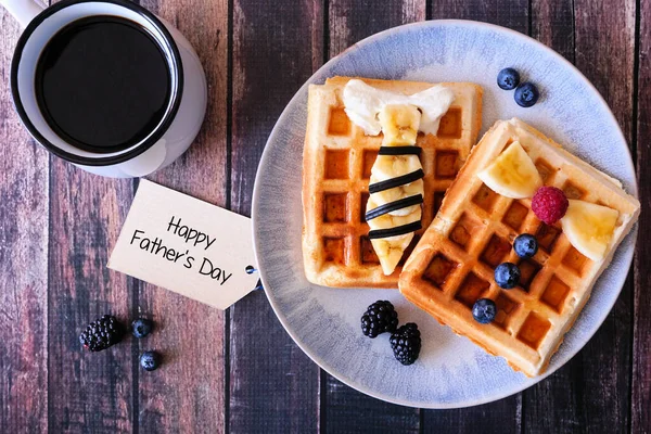 Fathers Day shirt waffles with necktie and bowtie with buttons. Homemade Fathers Day breakfast concept. Top down view table scene on a dark wood background.