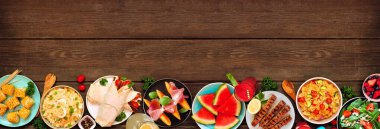 Koyu renk ahşap bir arka planda yaz yemekleri alt sınırı. Çeşitli serinletici salatalar, meyveler, ambalajlar ve ızgara şişler. Üst Manzara. Boşluğu kopyala.