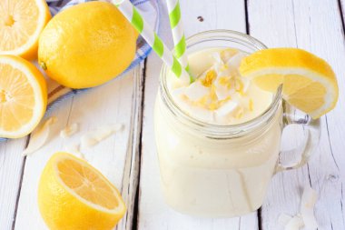 Kavanoz bardakta limonlu hindistan cevizli smoothie. Masa sahnesini beyaz ahşap arka planlı kapat.