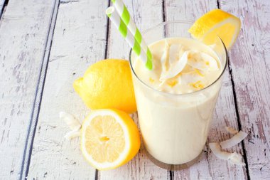 Limonlu, hindistan cevizli buzlu içecek. Masa sahnesini beyaz ahşap arka planlı kapat.