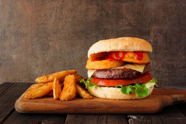 Patates dilimli soğan halkalı hamburger. Koyu bir arkaplan karşısında kenar görünüm tablosu.