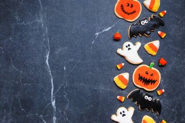 Cadılar Bayramı kurabiye tarafı sınırı. Fotokopi alanı olan karanlık bir taş zemin üzerinde. Hayaletler, yarasalar, fenerler ve mısır şekeri..