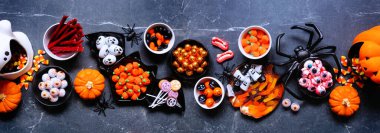 Cadılar Bayramı şeker masası sahnesi. Ürkütücü bir grup tatlı. Koyu taştan bir arkaplanda en üstteki görünüm.