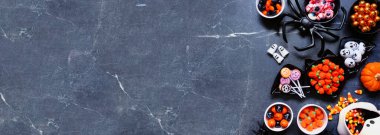 Cadılar Bayramı şeker mi şeker mi sınırı. Bir sürü ürkünç tatlı. Fotokopi alanı olan koyu taştan bir afiş arkaplanı üzerinde genel görünüm.