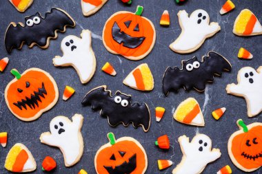 Halloween cookie background. Above view on dark stone. Ghosts, bats, jack o lanterns and candy corn. clipart