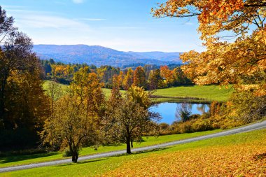 Woodstock, Vermont, ABD yakınlarındaki mavi gökyüzü altında dağları ve göleti olan renkli sonbahar manzarası