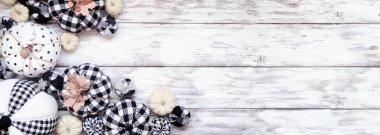 Modern çiftlik evinin sonbahar köşesi beyaz ahşap bir arka plan üzerinde. Siyah ve beyaz ekose ve desenli bez balkabakları. Kopyalama alanı ile genel görünüm.