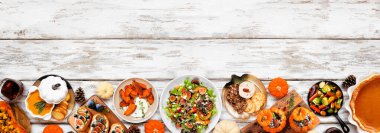 Lezzetli sonbahar yemeği alt sınırda. Beyaz ahşap arka planda üst manzara. Doldurulmuş balkabağı ve kabak, tatlı patates, mezeler, çorba, sebze ve balkabağı turtası..