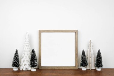 Noel, ahşap çerçeve ve ağaç süsüyle süslenir. Beyaz bir duvara karşı ahşap bir rafta kare çerçeve. Boşluğu kopyala.