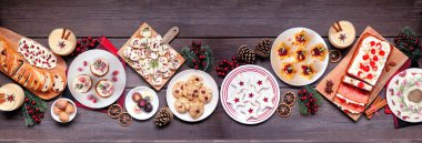 Noel yemeği masası sahnesi. Koyu renk ahşap afiş arkaplanda yukarıdan görünüyor. Çeşitli aperatifler ve lezzetli tatlılar. Uzayı kopyala Tatil partisi yemek konsepti.