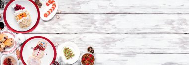 Noel kahvaltısı köşesi sınırı. Beyaz ahşap bir arka planda tepeden aşağı manzara. Eğlenceli tatil yemekleri konsepti. Noel Baba ve Kardan Adam krepleri, çörekler, meyve ve mısır gevrekleri. Boşluğu kopyala.