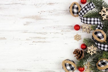 Beyaz ve siyah gingham kurdele, takılar ve dallardan oluşan bir Noel kenarı. Beyaz ahşap arka planda tepeden aşağı manzara. Boşluğu kopyala.