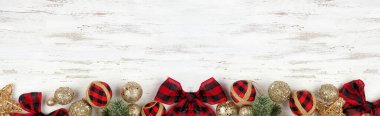 Kırmızı ve siyah gingham süslerinden, dallardan ve altın takılardan oluşan bir Noel ağacı. Beyaz ahşap bir arka planda tepeden aşağı manzara. Boşluğu kopyala.