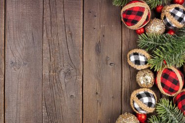 Kırmızı, siyah ve beyaz gingham süsleri, dallar ve takılardan oluşan bir Noel kenarı. Koyu bir ahşap arka planda tepeden aşağı manzara. Boşluğu kopyala.