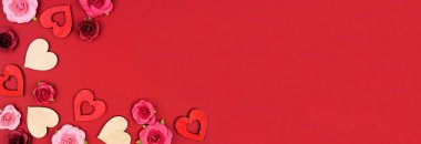 Sevgililer Günü 'nün tahta kalpler ve güllerle dolu köşesi. Kırmızı fonda yukarıdan aşağıya doğru bir manzara. Boşluğu kopyala.
