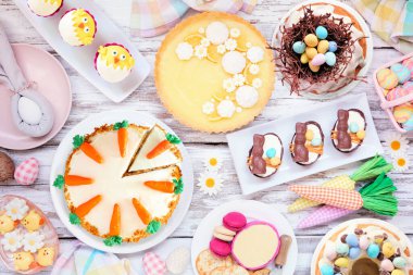 Paskalya ya da bahar tatlı masası sahnesi. Beyaz ahşap arka planda yukarıdan aşağıya doğru. Limonlu tart, kekler, Paskalya yumurtası, havuçlu kek ve çeşitli tatlılar..