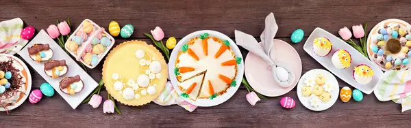 Paskalya ya da bahar tatlı masası sahnesi. Koyu ahşap bir arkaplanda manzaranın üstünde. Limonlu tart, kekler, Paskalya yumurtası, havuçlu kek ve çeşitli tatlılar..