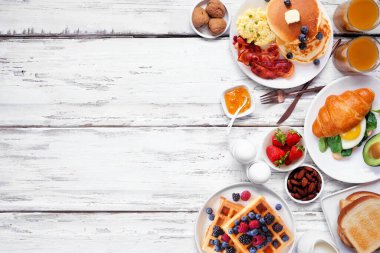 Beyaz ahşap arka planda kahvaltı ya da brunch kenarı. Yukarıdan aşağıya doğru. Çeşitli tatlı ve tuzlu yiyecekler..
