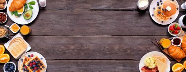 Kahvaltı ya da brunch, arka planda koyu ağaç pankartıyla çifte sınır. Genel bakış. Tatlı ve lezzetli yiyecek koleksiyonu.