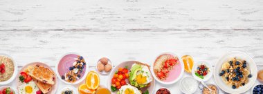 Sağlıklı kahvaltı ya da arka planda beyaz ahşap pankartta kahvaltı. Üst Manzara. Avokado tostu, meyve püresi, yulaf, yoğurt ve çeşitli besin maddeleri..