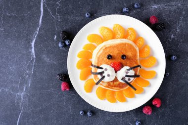 Aslan suratlı şirin çocuk temalı kahvaltı krepi. Masanın üstünde, koyu renkli bir arkaplanda..