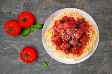 Ev yapımı spagetti ve domates soslu köfte. Koyu renkli bir arkaplanda en üstteki tablo sahnesi.