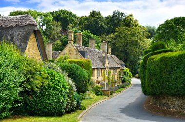 Cotswolds köyünde Gloucestershire, İngiltere 'de sazdan çatı evi olan güzel bir cadde.