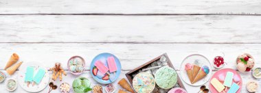 Soğuk yaz yemekleri alt sınırında. Bir grup dondurma, buzlu şeker ve dondurulmuş şeker. Pastel renkler. Beyaz ahşap bir arkaplanda tepeden aşağı görünüm.