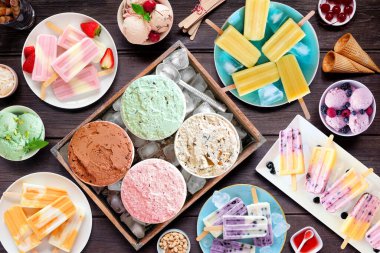 Harika bir yaz yemeği masası sahnesi. Çeşitli serinletici dondurmalar, dondurmalar ve dondurulmuş şekerlemeler. Koyu bir ahşap arka planda genel görünüm.